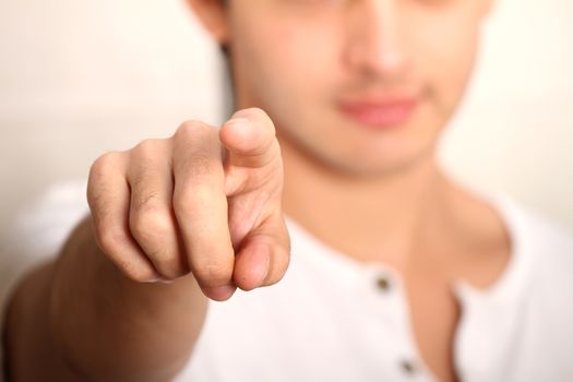 A young man pointing at you. Focus on Finger.