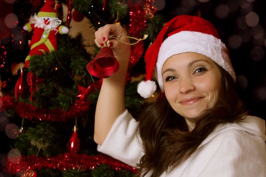 Santa woman helper ringing the bell under Christmas tree