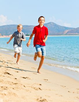 Two happy kids running along beach