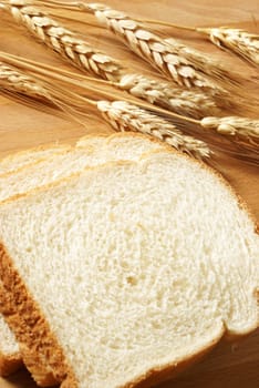 A closeup of some fresh baked bread that has been sliced on a wooden board.