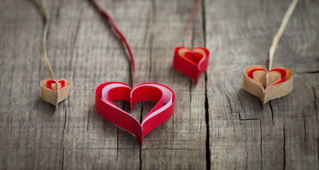 Four Handmade Paper hearts on wooden background.