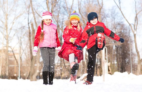 Boy and girls playing with snow in winter park, spending time together outdoors