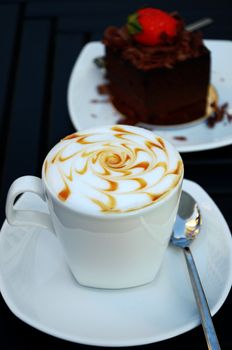 Cup of coffee with a chocolate cake on the white plate