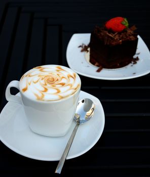 Cup of coffee with a chocolate cake on the white plate