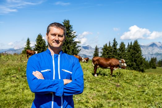 Herdsman standing in front of cows in alpine mountains