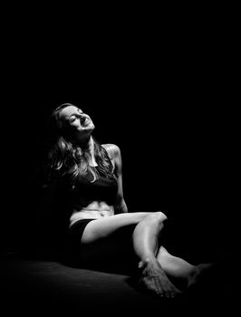 Young muscular woman under bright light in a studio