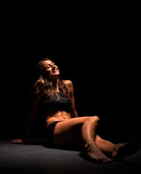 Young muscular woman under bright light in a studio