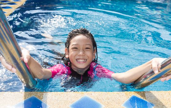 Girl relaxing on the side of a swimming pool