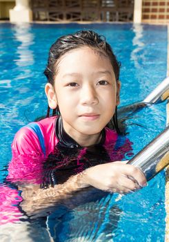 Girl relaxing on the side of a swimming pool