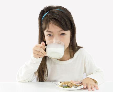 Cute girl drinking a glass of milk and eating a cake