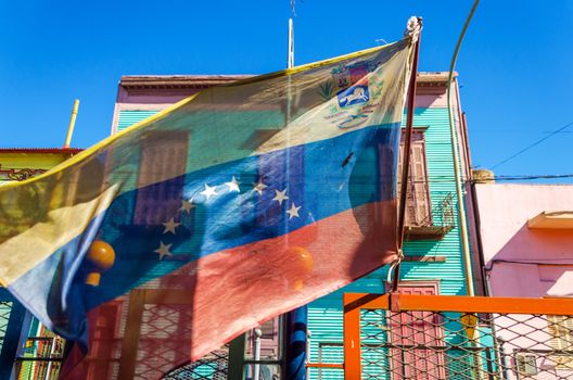 Venezuelan flag blowing in the wind with brightly colored buildings