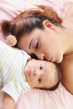 Hispanic woman kissing newborn