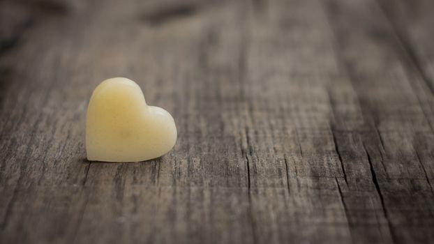 A beige heart out of wax on wooden background
