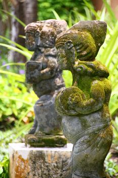 Tipycal balinese statues prepresenting dancers and musicians carved from local volcanic stone and covered in moss