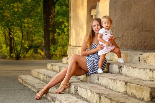 Family, mother and daughter are sitting on the steps of a building