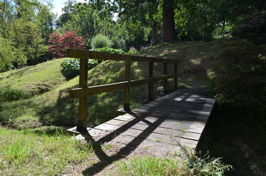 A small wooden bridge in a landscaped formal garden in England.