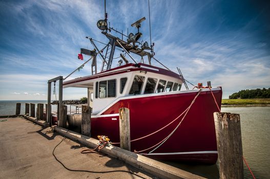 Red boat docked at a wharf of a small village in New Brunswick Canada