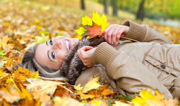Portrait of a nice young woman surrounded by autumn leaves