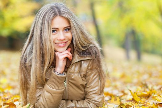 Young woman lying in a park in autumn season