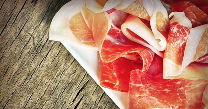 Slices of prosciutto on old wood