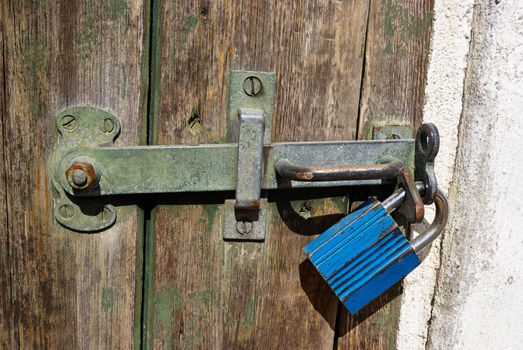 Wooden door locked with a heavy metal lock padlock