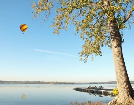 hot air balloon floating over a lake on a beautiful spring morning