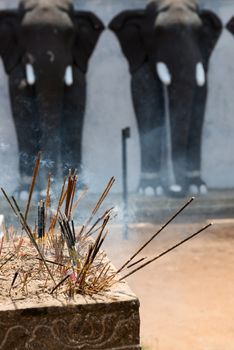 Incense sticks in a Buddhist temple with elephants on background