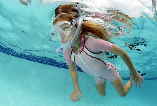 pretty girl swimming underwater in pool in summer