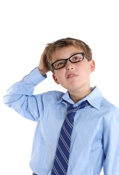 School boy scratches head whilst thinking of an idea or answer or may even be unsure or confused.  White background.