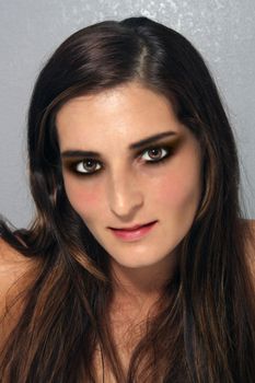 A close-up of a lovely young brunette with a textured grey background.