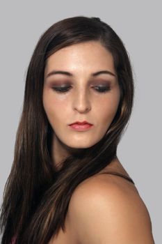 A close-up of a lovely young brunette looking down and over her left shoulder.