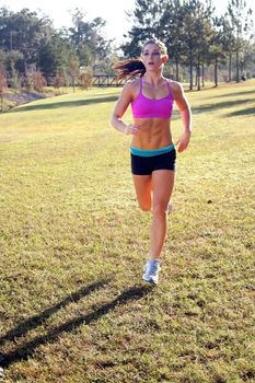 A lovely young athlete with remarkable abdominal musculature jogging outdoors.  Generous copyspace.