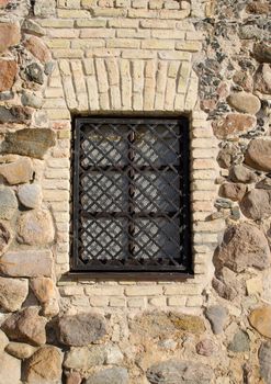 window with iron protective bar grating in retro masonry brick stone building house wall.
