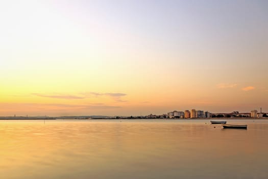 The city and the river with two small boats at sunset.