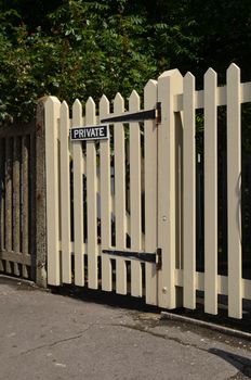 A wood picket gate with a private sign attached.