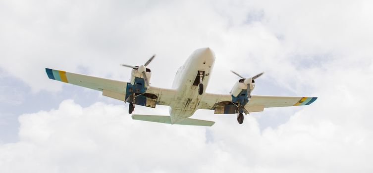 Small plane descending against a cloudy sky