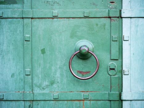 metallic ring handle over green door
