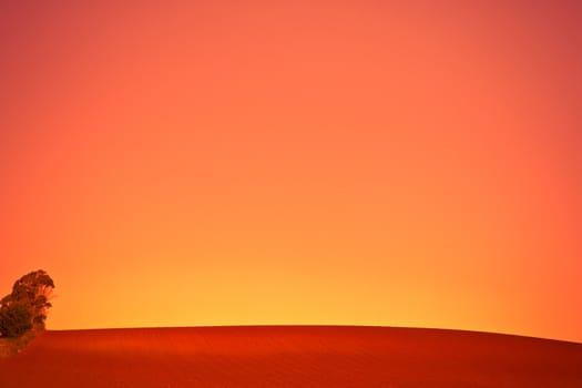 Background image of a vivid orange sunset over newly ploughed agricultural fields left fallow awaiting a crop in farmland, with copyspace