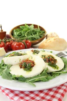 stuffed mozzarella with dried tomatoes and arugula on a light background