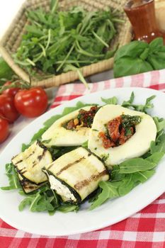 Courgette rolls and filled mozzarella and rocket salad on a bed