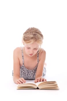 young girl reading a book against white background lying down on floor of studio
