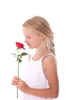 young girl in white dress smelling a red rose against white background