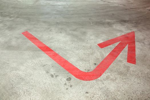red arrow on the concrete floor of empty parking garage