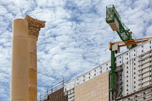 An old Corinthian style column stands proud alongside an ultra modern construction in the background