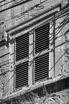 The window on the Executioner's House in Vittoriosa.  Note the executioner's symbol and motif in the stone above the window.