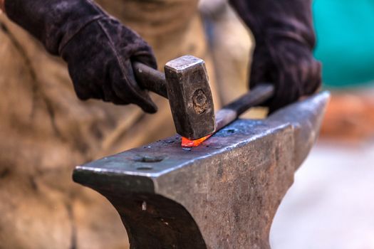 Blacksmith working on metal on anvil at forge detail shot