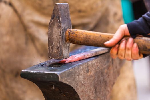 Blacksmith working on metal on anvil at forge detail shot