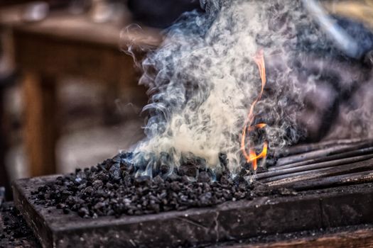 Blacksmith working on metal on anvil at forge detail shot