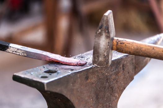 Blacksmith working on metal on anvil at forge detail shot