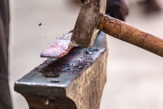 Blacksmith working on metal on anvil at forge detail shot